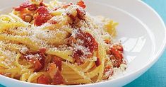 pasta with bacon and parmesan cheese in a white bowl on a blue tablecloth