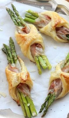 asparagus wrapped in ham and cheese on top of parchment paper