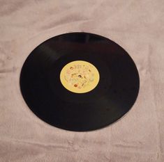 a black record with a yellow label on it sitting on a white sheeted surface