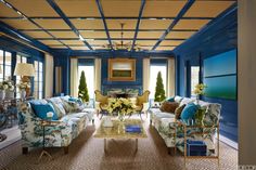 a living room with blue walls and floral couches, chairs, coffee table and chandelier