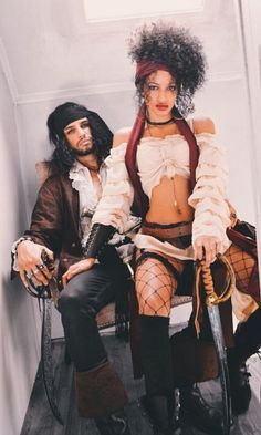 a man and woman dressed up as pirates sitting next to each other on a chair