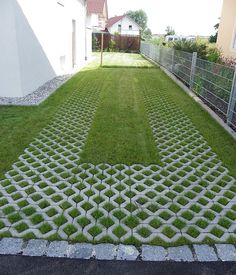 a yard with grass and cement blocks in the shape of an arrow, next to a house