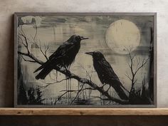 two black birds sitting on top of a tree branch in front of a full moon