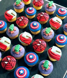 cupcakes decorated with captain america and spider - man icing on a tray