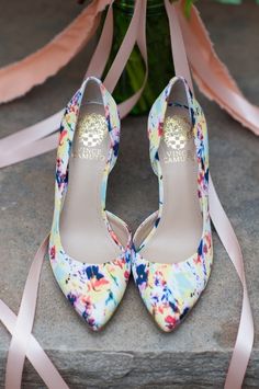 a pair of colorful shoes sitting on top of a stone slab next to a bouquet of flowers