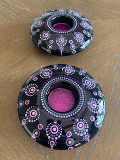 two black and pink glass vases sitting on top of a wooden table