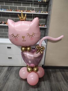 a pink cat balloon sitting on top of a pile of balloons