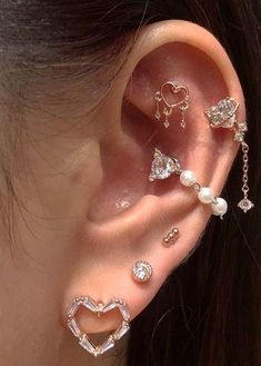 a woman wearing ear piercings with pearls and hearts on the inside of her ear