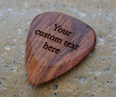 a wooden guitar pick with the words your custom text here engraved on it's side