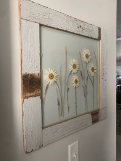 an old window frame with daisies on the outside and in between it is a light switch plate