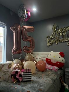 a bed with balloons and hello kitty decorations on top of it, next to a large number 15 balloon