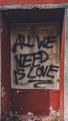 graffiti is spray painted on the side of an old door in front of a red wall