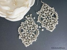 a pair of earrings sitting on top of a table next to a white cloth flower