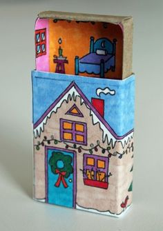 a small box with a house painted on the front and side, sitting on a white surface