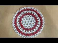 a beaded red, white and black circle on a wooden table with beads in the middle