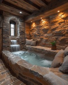 an indoor hot tub with water running down the side and pillows on the floor next to it