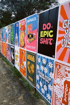 a long line of colorful posters on the side of a building with trees in the background