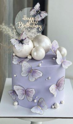 a purple cake with butterflies and eggs on it's top is sitting on a table