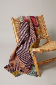 a chair with a blanket on top of it sitting next to a wooden frame and wicker seat