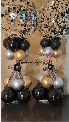 two black and white balloons with some silver and gold confetti on them,