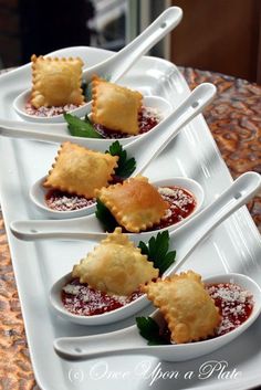 four small white dishes filled with ravioli and garnished with parmesan cheese