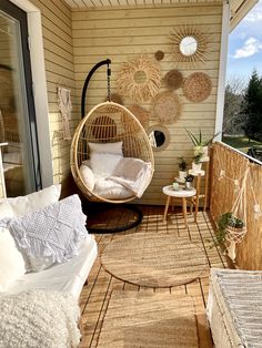 a porch with a hanging chair and other furniture on the outside patio, along with an area rug that looks like it has been made out of wood