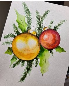 a watercolor painting of two christmas ornaments on a white paper with green and red leaves