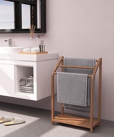 a white sink sitting next to a wooden stand with towels on it and a mirror above it