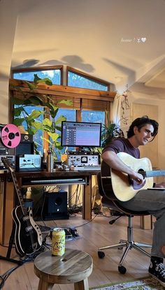 a man sitting in front of a computer desk with a guitar on top of it