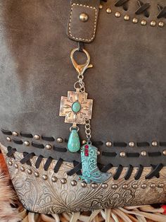 a purse with a cross on the front and a turquoise bead charm hanging from it