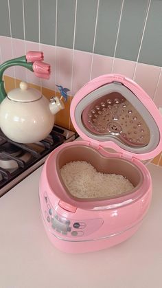 a pink microwave oven with rice in it and a teapot on the stove top