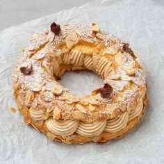 a cake covered in powdered sugar and nuts on top of wax paper with crumbs