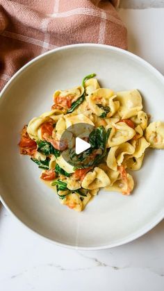 a white plate topped with pasta and spinach