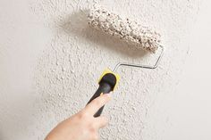 a person using a paint roller to paint a wall