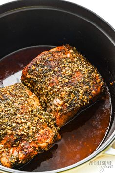 two pieces of meat in a skillet with sauce and seasoning on the side