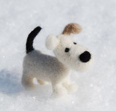 a small white and black dog standing in the snow with it's nose up