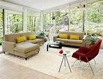 a living room filled with lots of furniture next to large glass windows covered in trees