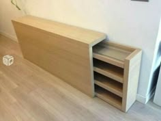 a wooden shelf sitting on top of a hard wood floor next to a white wall