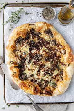 a pizza sitting on top of a pan covered in cheese and toppings next to a knife