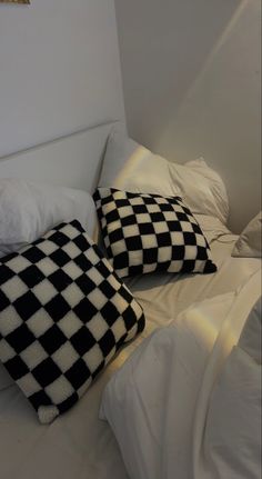 two black and white pillows sitting on top of a bed next to eachother