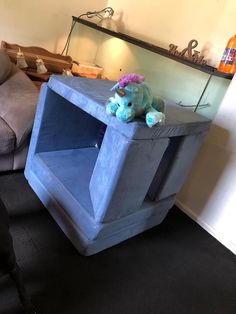 a stuffed animal sitting on top of a blue shelf in a living room next to a couch