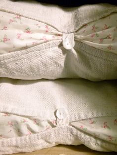 an unmade bed with white sheets and pink flowers on it