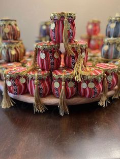 a table topped with lots of red and gold vases covered in tassels