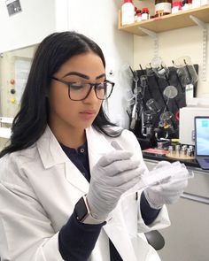 a woman in white lab coat and glasses looking at something