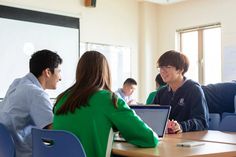 three people sitting at a table with laptops