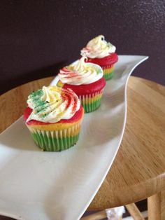 three colorful cupcakes on a white plate