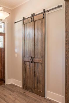 an empty room with two wooden doors and a chandelier hanging from the ceiling