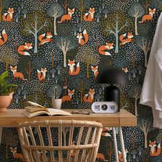 a desk with a lamp, chair and wallpaper in the shape of foxs