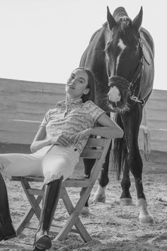 a woman sitting in a chair next to a horse