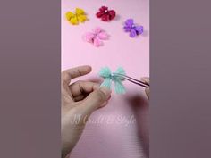 a person is holding a pair of scissors in front of some paper flowers on a pink background